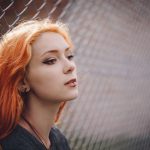 girl leaning against a net fence